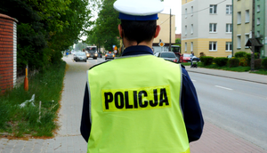 Policjant w kamizelce odblaskowej z napisem policja.